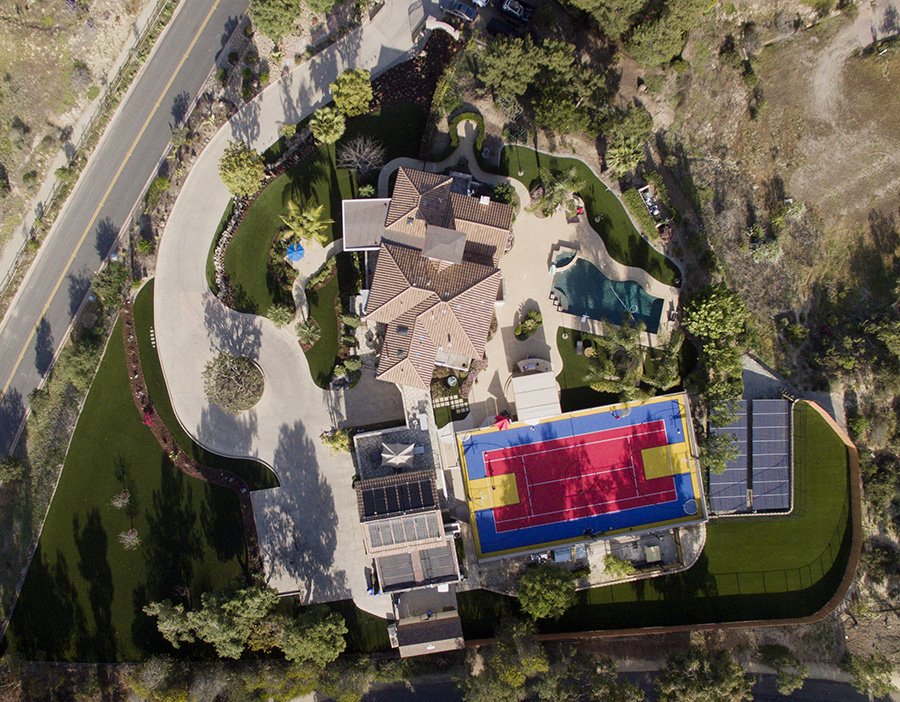 Drone shot of artificial turf installation with multi sport surface court in backyard.